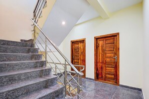 A staircase with metal railings leading to a landing with two wooden doors.