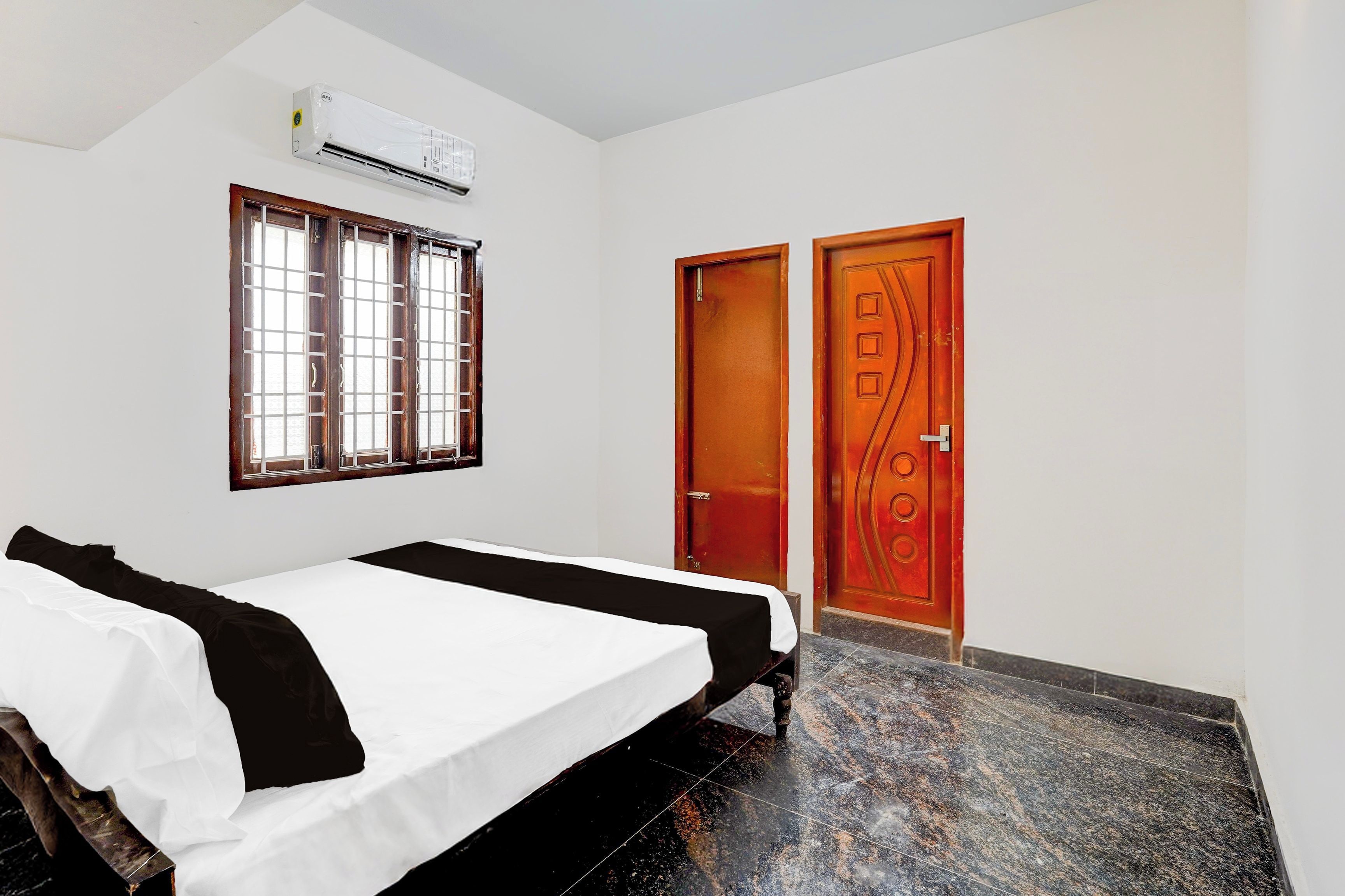 Een kamer met een bed, raam, airconditioning en een deur.