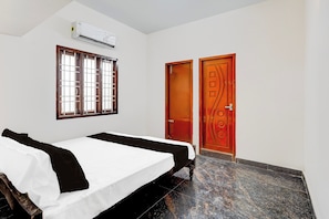 Una habitación con cama, ventana, aire acondicionado y puerta.