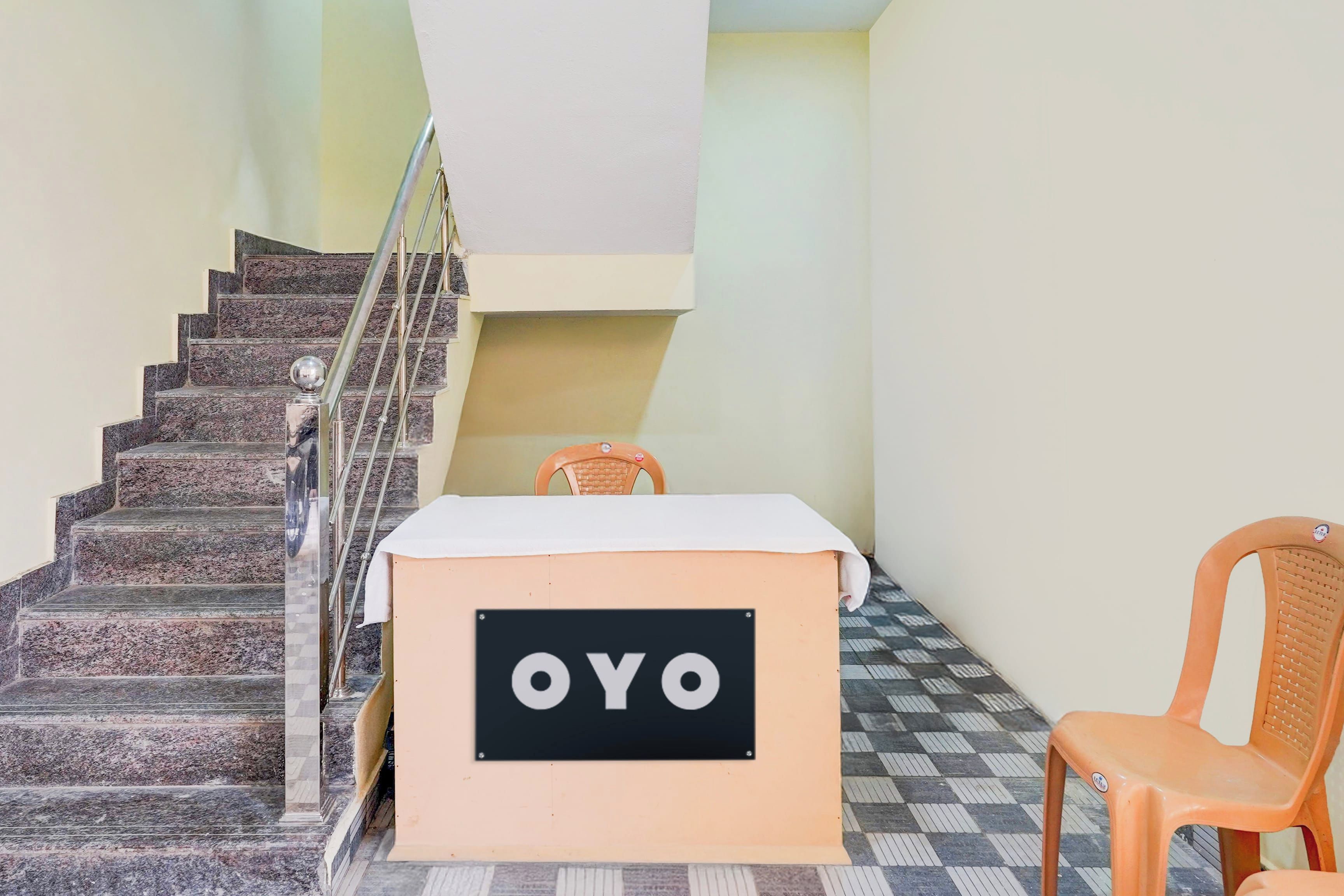 A staircase with a checkered floor, a chair, and a table with a sign that reads 'OYO'.