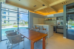 Une cuisine moderne avec une table en bois et des chaises en osier, donnant sur une piscine.