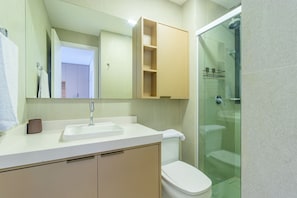 Un baño con un lavabo blanco, un inodoro, una cabina de ducha de cristal y un espejo sobre el lavabo.