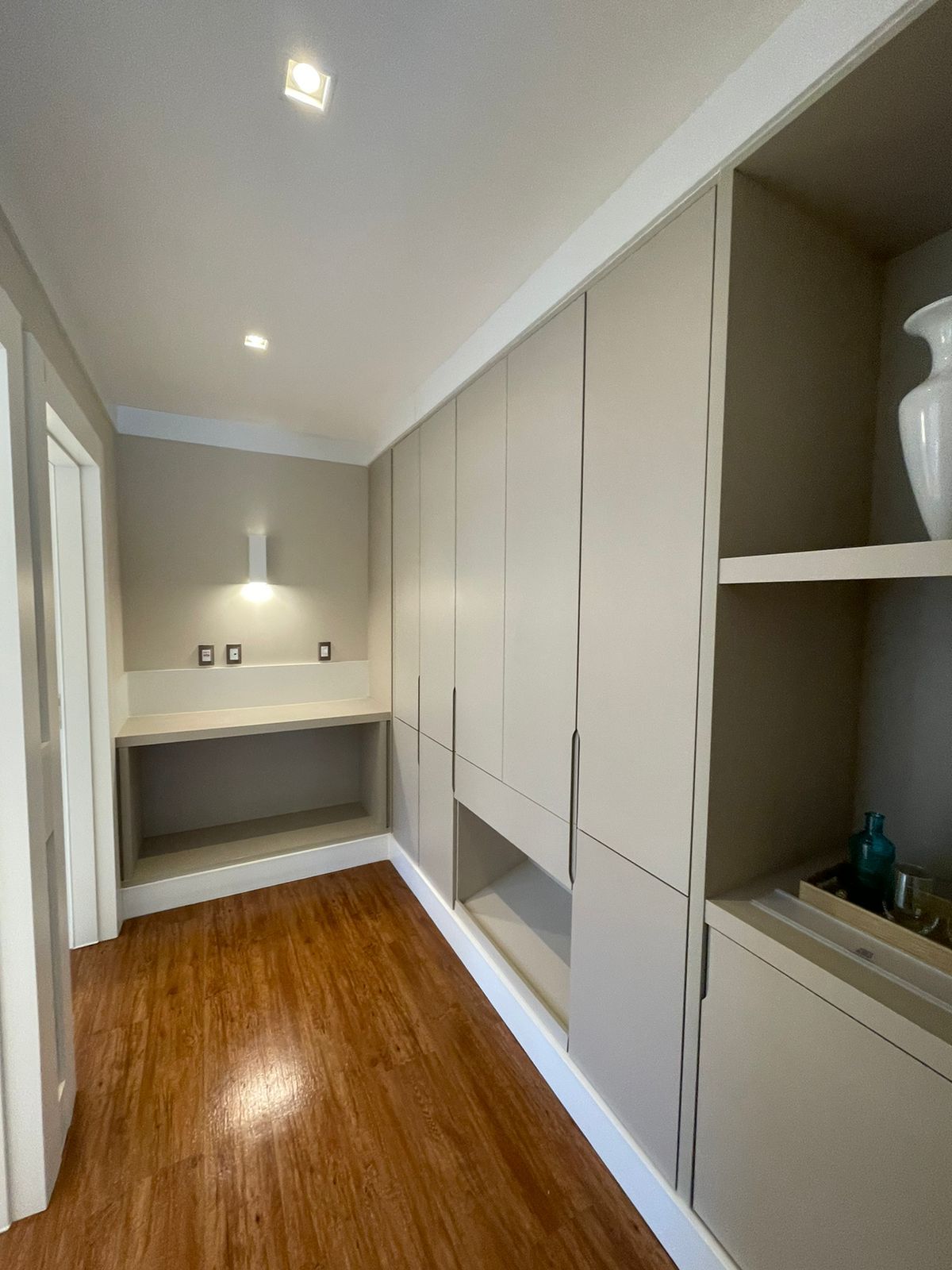 Un couloir doté d’un plancher en bois, d’un banc intégré et d’une grande armoire à plusieurs portes.