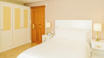 Habitación de hotel con una cama grande, dos mesitas de noche con lámparas, un armario de madera y una puerta.