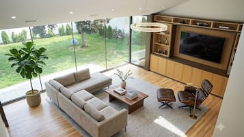 Un salon moderne avec un canapé d’angle, une table basse et un téléviseur fixé au mur.