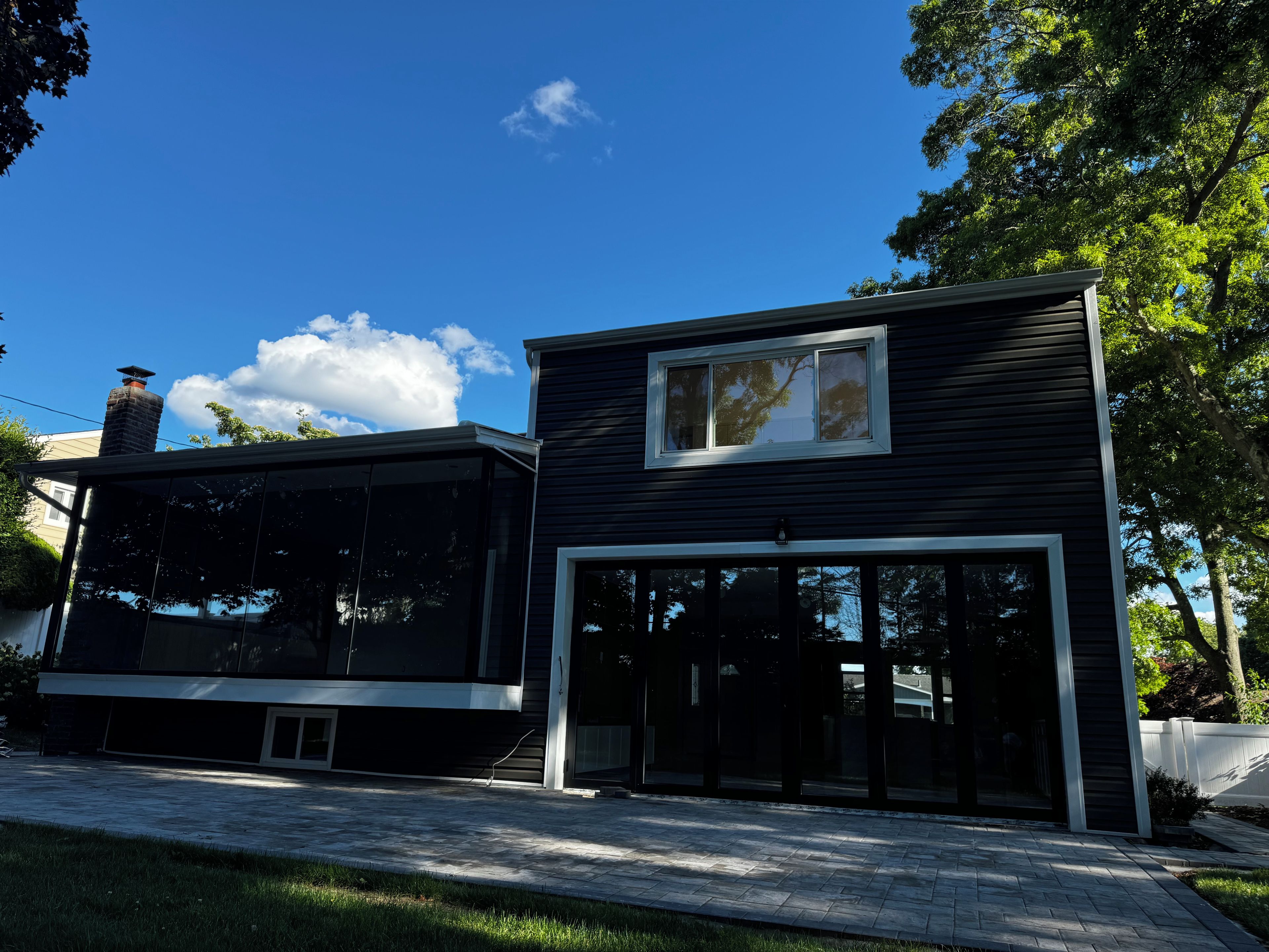 Ett modernt hus i två våningar med ett stort glasfönster och en skorsten.