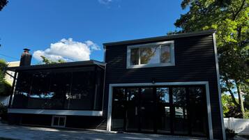 Une maison moderne à deux étages, dotée d’une grande baie vitrée et d’une cheminée.