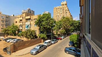 A street view with parked cars, buildings, and trees.