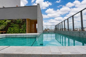 Ein modernes Gebäude mit Pool auf dem Dach, umgeben von einer Stadtansicht.
