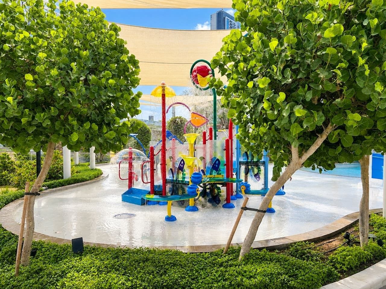 A playground with various play structures surrounded by greenery and trees.