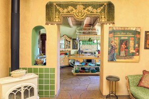 A kitchen with a stove, a hanging pot rack, and a tiled backsplash. - Taos luxury upscale private secluded gourmet kitchen mountain views upgrade (Arroyo Seco)