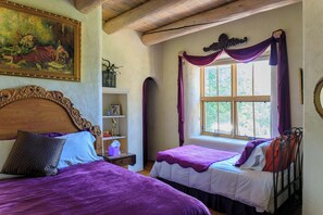 A room with two beds, a wooden headboard, a window with purple curtains, and a painting on the wall. - Taos luxury upscale private secluded gourmet kitchen mountain views upgrade (Arroyo Seco)