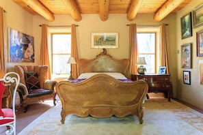 A bedroom with a large bed, a chair, a nightstand, and a painting on the wall. - Taos luxury upscale private secluded gourmet kitchen mountain views upgrade (Arroyo Seco)