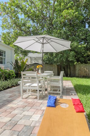 A patio with a table and chairs, an umbrella, and a small garden area.