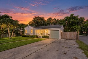 Une maison de plain-pied avec un porche à l’avant, un garage et une clôture en bois.