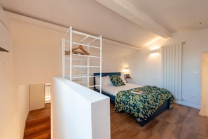 A bedroom with a bed, a white wardrobe, a wooden hanger rack, and a nightstand with a lamp. - 2 Bedrooms 2 Baths · Lift · 6 min to Accademia (FIRENZE)