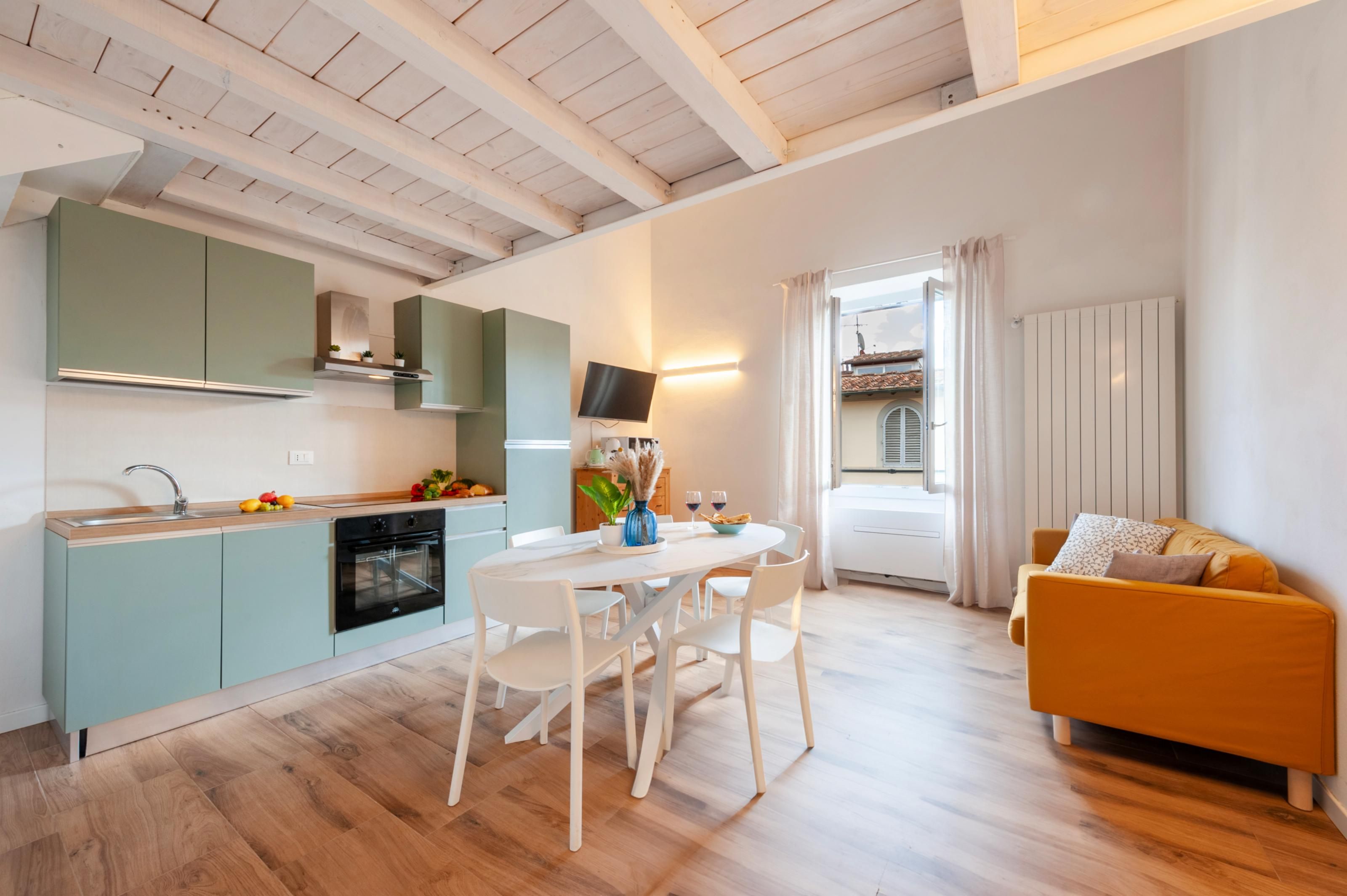 Une cuisine moderne avec un coin repas, un canapé et une vue sur un bâtiment à l’extérieur.