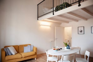 A modern living space with a yellow sofa, a round dining table, and a staircase with a black railing. - 2 Bedrooms 2 Baths · Lift · 6 min to Accademia (FIRENZE)