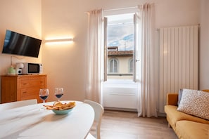 A hotel room with a bed, a dining table with a bowl of food and wine glasses, a television, and a window with curtains. - 2 Bedrooms 2 Baths · Lift · 6 min to Accademia (FIRENZE)
