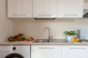 A modern kitchen with white cabinets, a stainless steel sink, and a washing machine. - Duomo 10 min · 2 separate bedrooms · Lift (FIRENZE)