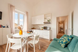 A modern kitchen with white cabinets, a dining table with chairs, a microwave, and a window with curtains. - Duomo 10 min · 2 separate bedrooms · Lift (FIRENZE)
