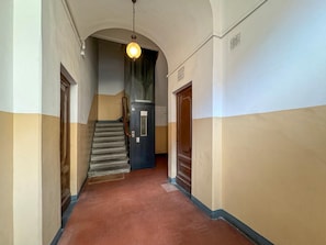 A hallway with a staircase, a door with a sign, and a hanging light fixture. - Duomo 10 min · 2 separate bedrooms · Lift (FIRENZE)