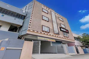 Un edificio de varios pisos con un cartel que indica 'OYO Grand Palace', mostrando que hay habitaciones con aire acondicionado.