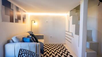 Una sala de estar moderna con un sofá, un tapete estampado y una escalera.