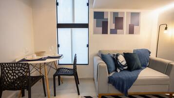 A modern living room with a sofa, a dining table with chairs, and a large window.