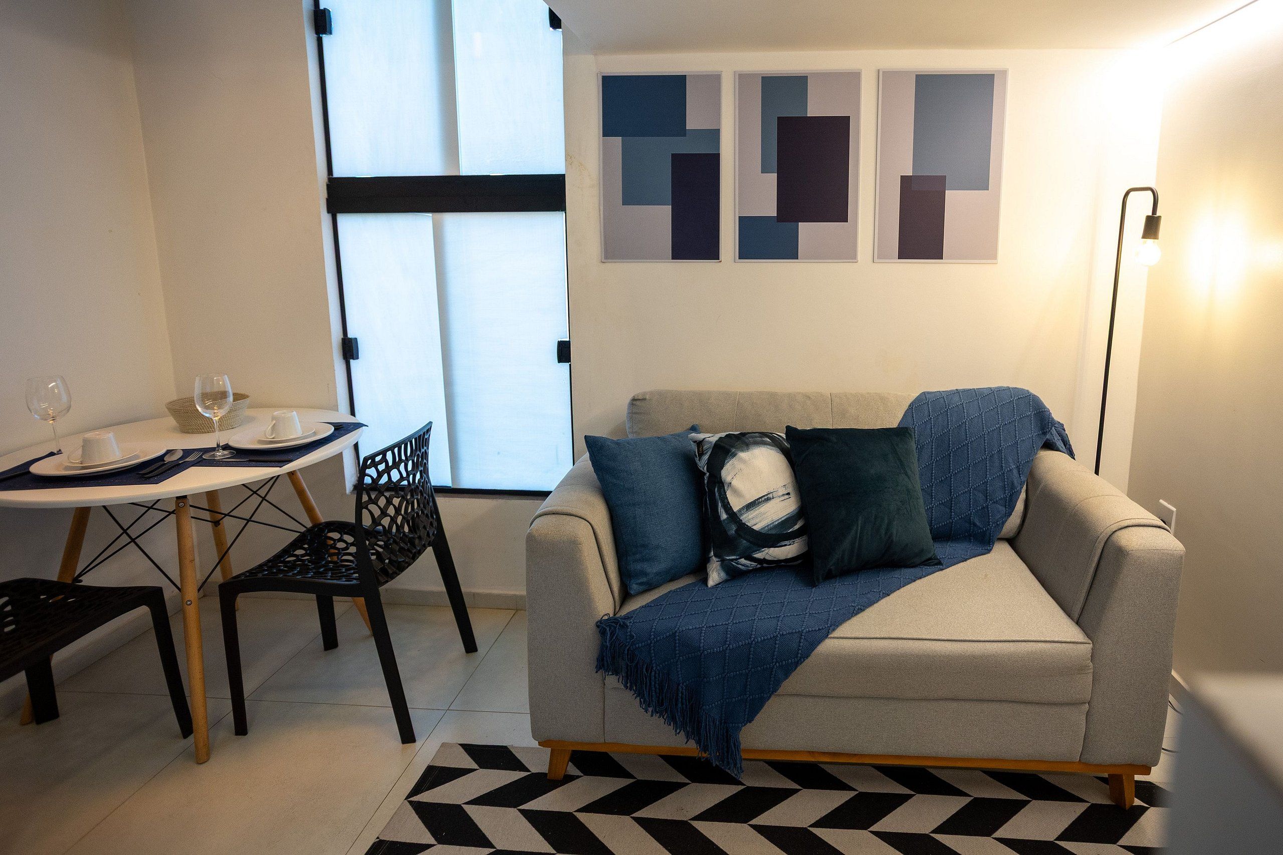 Un salon moderne avec un canapé, une table à manger et des chaises, et un mur orné d’œuvres d’art abstraites.