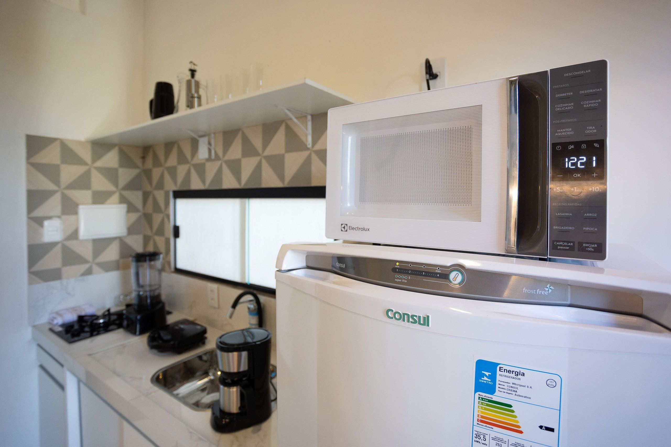 A kitchenette with a white refrigerator, a microwave, and a coffee maker.