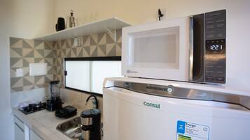A kitchenette with a white refrigerator, a microwave, and a coffee maker.