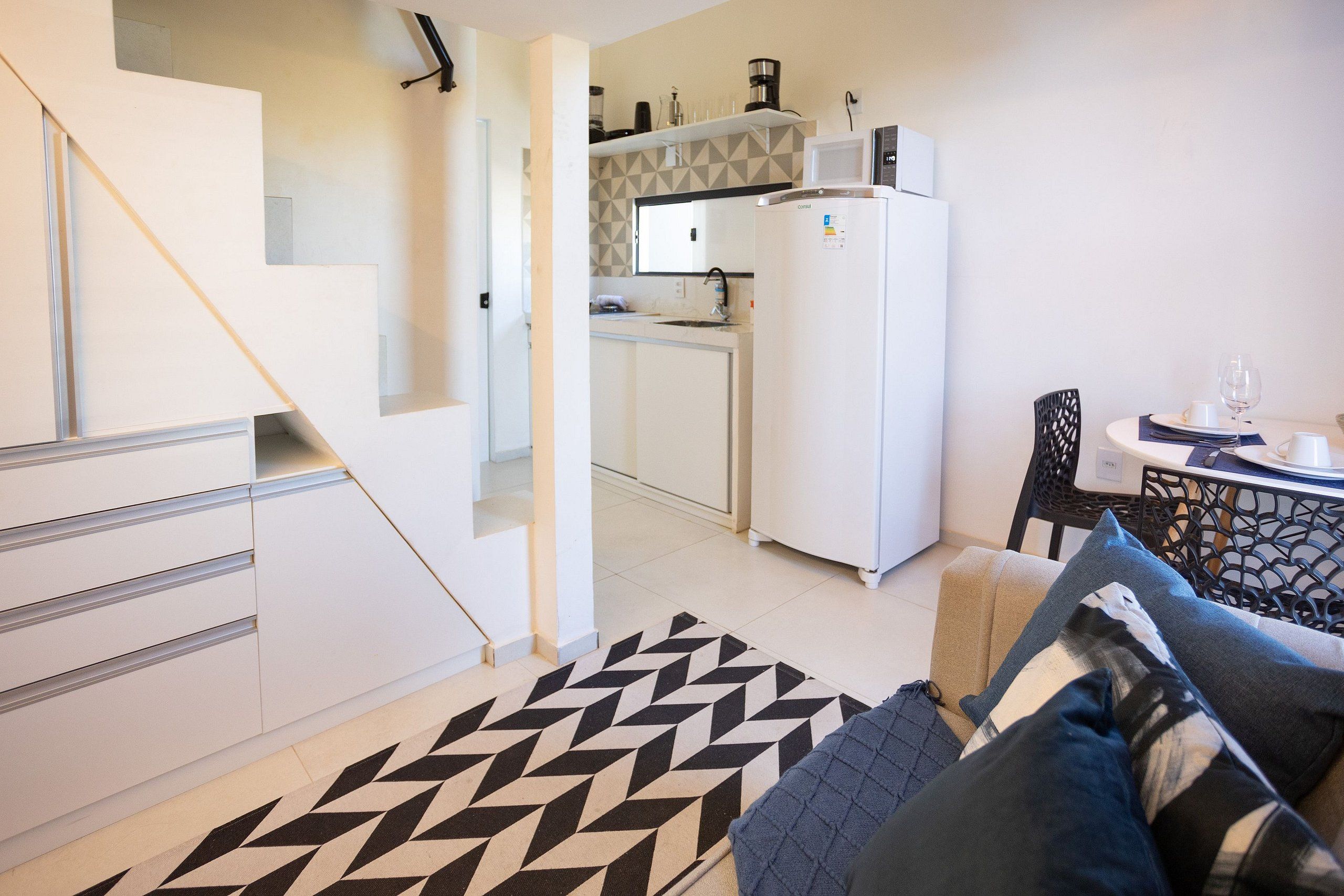 A compact living space with a kitchenette, a dining area, and a staircase.