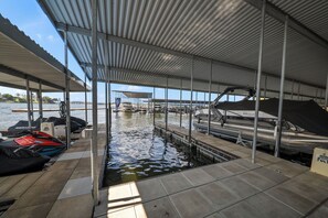 Un muelle cubierto con un canal de agua que conduce al mar, embarcaciones amarradas en el muelle y una vista despejada del mar al fondo.