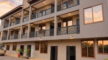 A multi-story hotel with balconies, large windows, and a paved entrance area with potted plants.