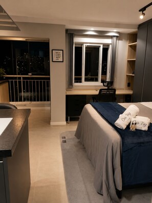 A modern bedroom with a bed, desk, and a view of the city at night. - Vibe 1604 (São Paulo)