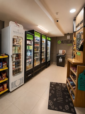 L’intérieur d’une épicerie, avec des rayons réfrigérés étiquetés « Bières », « Produits frais » et « Produits surgelés ».