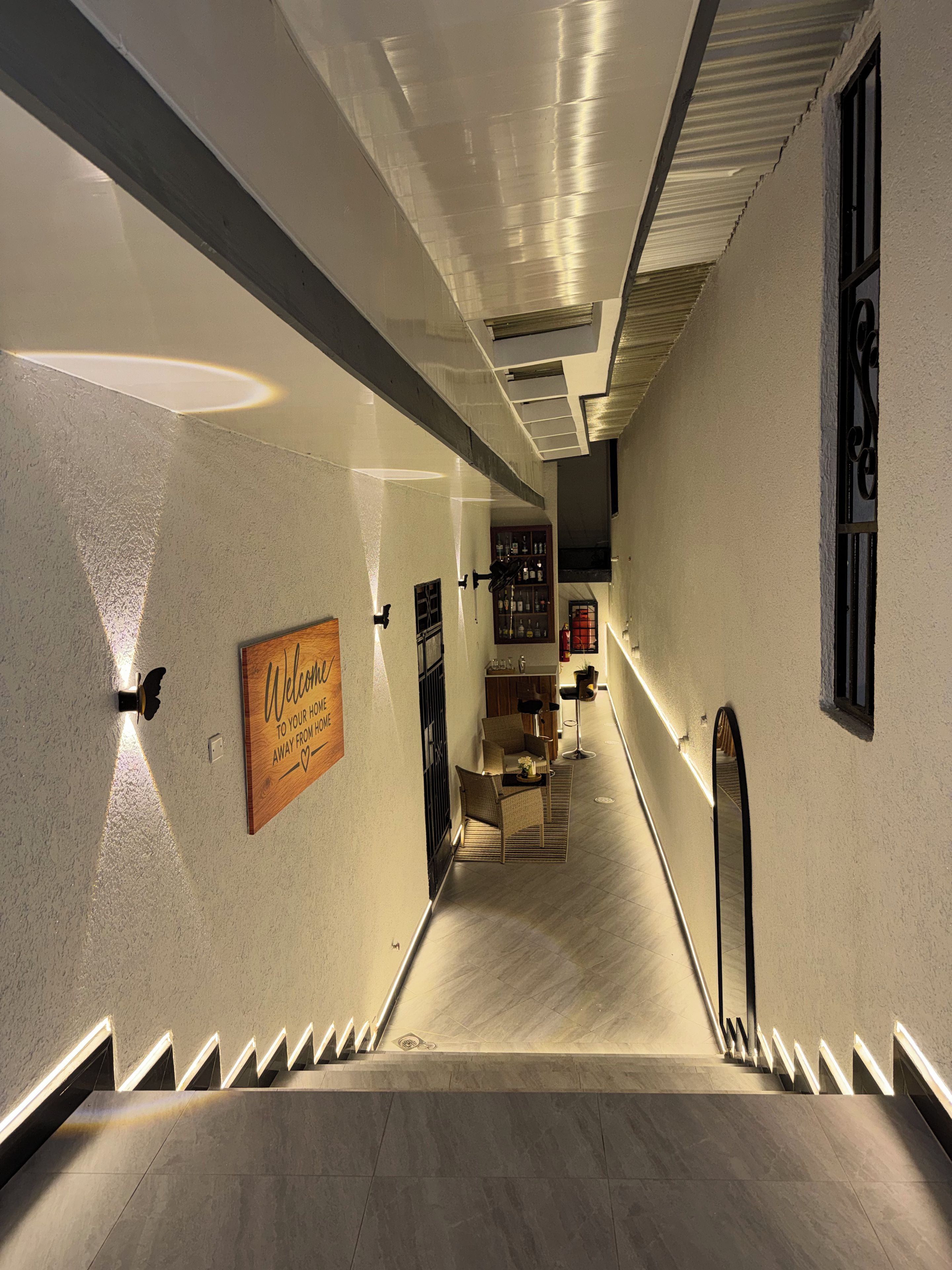 Un couloir d’hôtel avec un escalier, un panneau d’accueil et un espace bar.