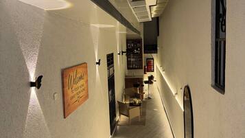 Un couloir d’hôtel avec un escalier, un panneau d’accueil et un espace bar.