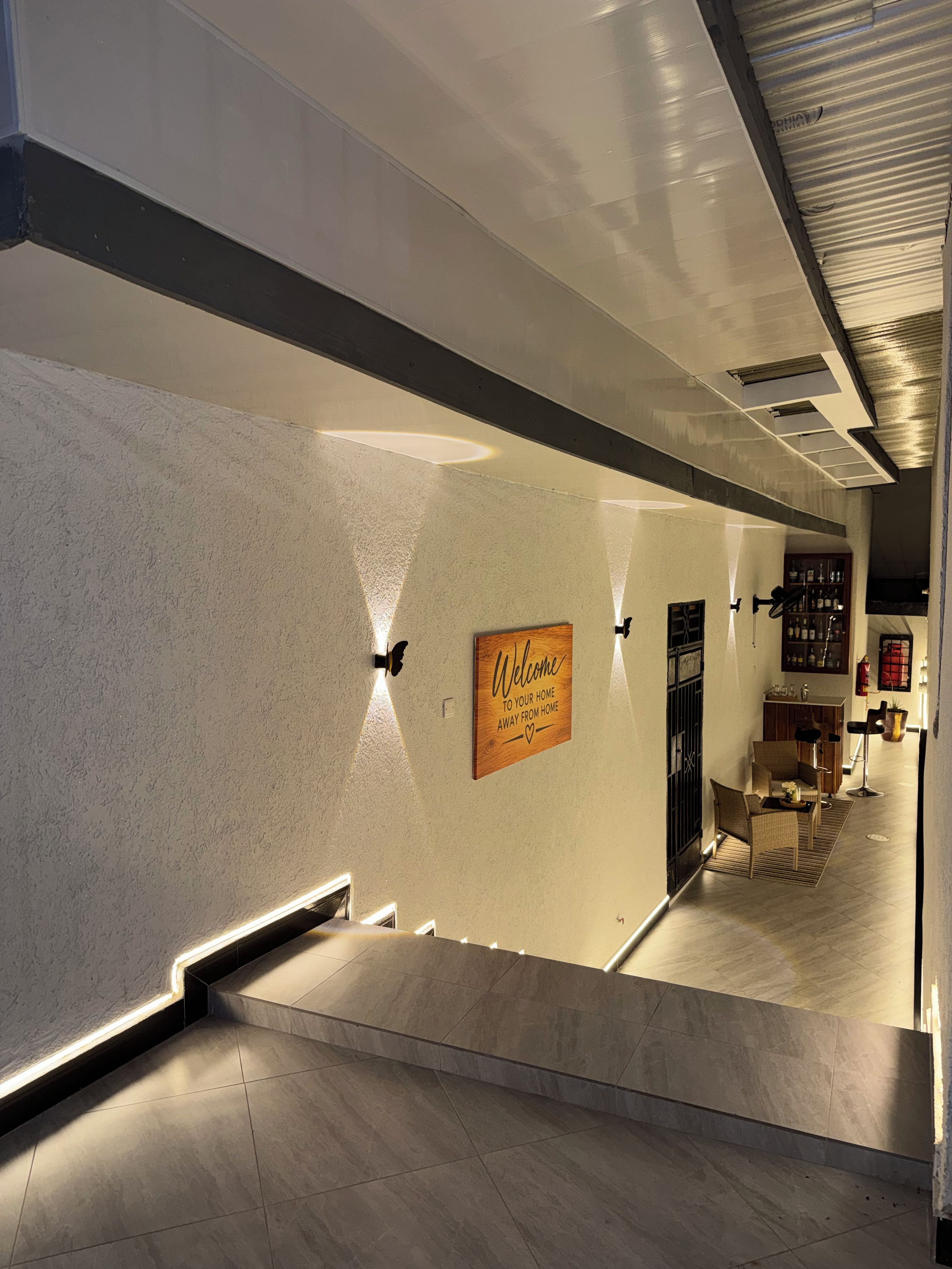 Un intérieur moderne agrémenté d’une enseigne accueillante, d’un escalier et d’un espace salon.