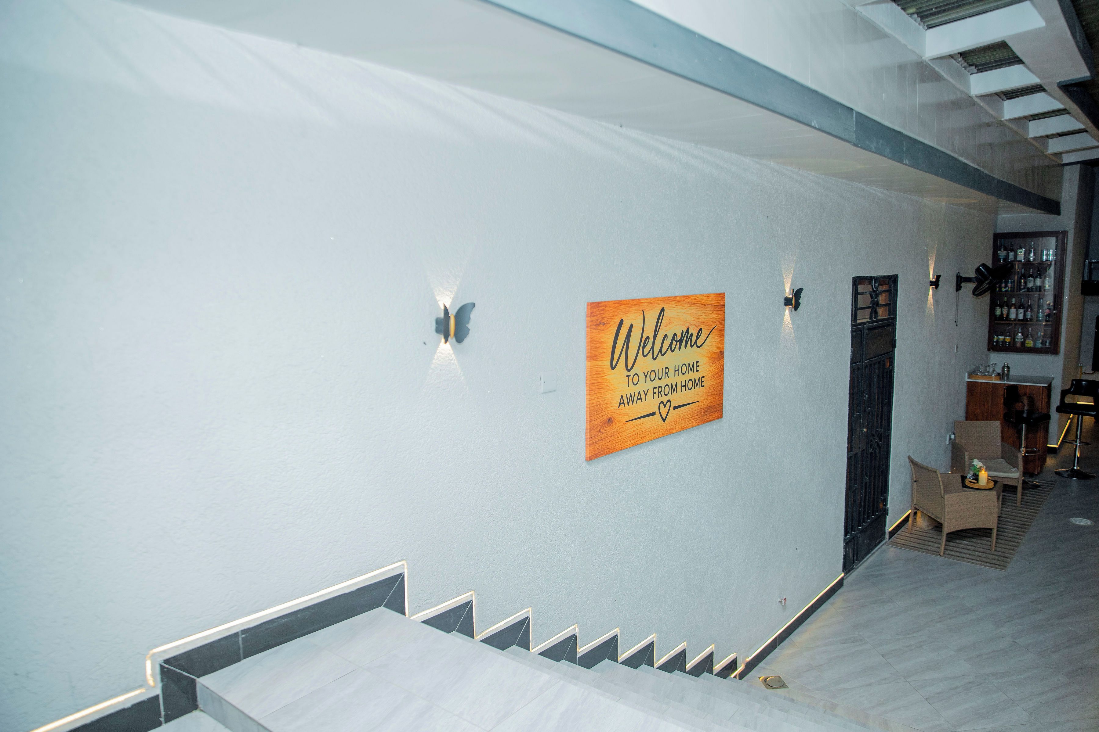 A modern interior with a staircase, a welcome sign, and a bar area.
