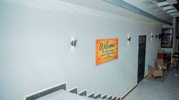 A modern interior with a staircase, a welcome sign, and a bar area.