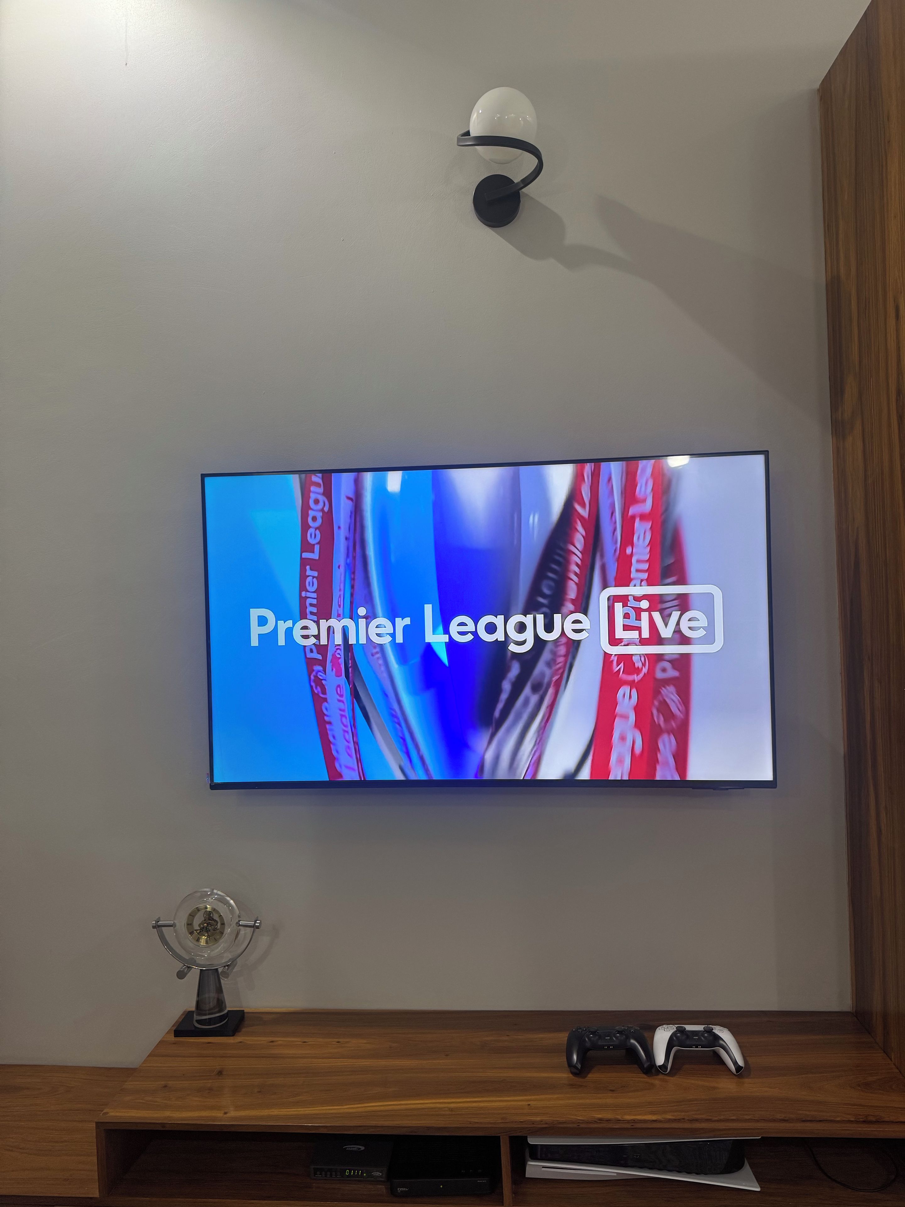 A television mounted on a wall displaying 'Premier League Live'.