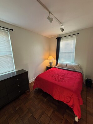 A bedroom with a bed, a dresser, a lamp, and a ceiling light. - Steps from IU Campus & Jacobs School - 1BR Apartment (Bloomington)