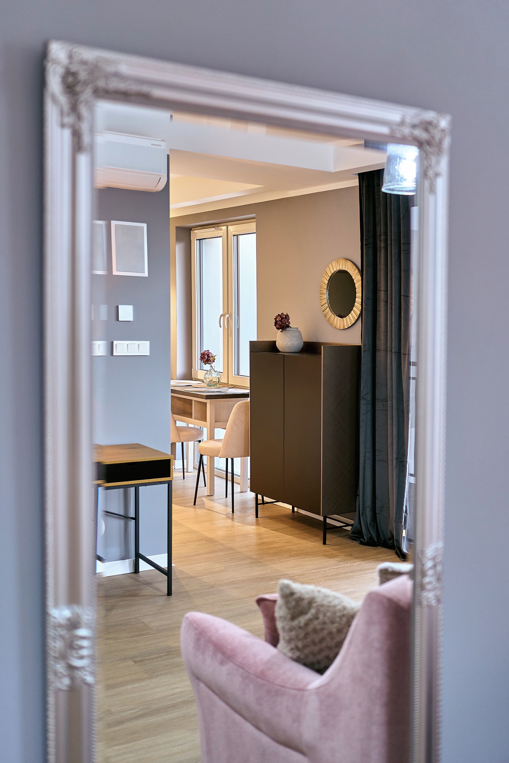 Een modern interieur met een eethoek, een bank en een spiegel die de ruimte weerspiegelt.