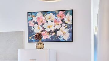 Una cocina moderna con un refrigerador blanco, una mesa de comedor con individuales y un florero con flores sobre la encimera.