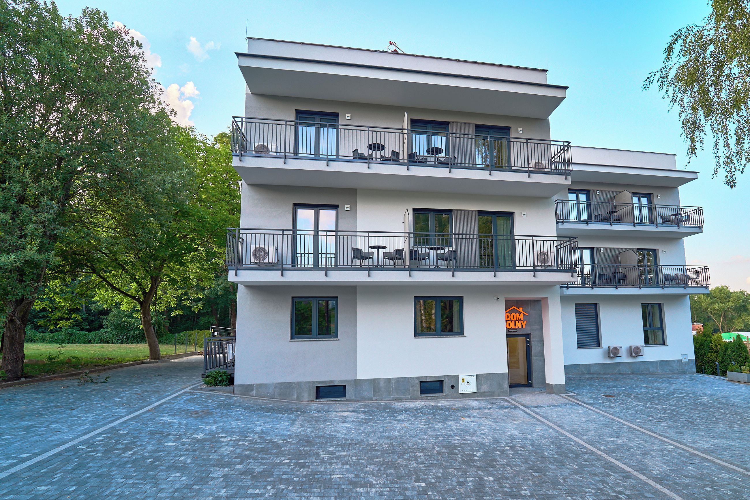 A multi-story building with balconies, a central entrance, and a paved courtyard.