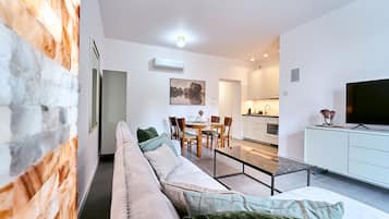 A modern living room with a sofa, dining table, and kitchen area.