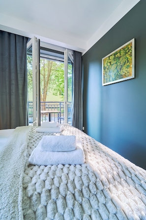 A bedroom with a large bed, a balcony, and a painting on the wall. - Dom Solny (Polanica-Zdrój)