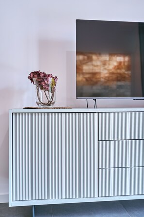 Un mueble de entretenimiento blanco y acanalado con un televisor de pantalla plana montado encima.